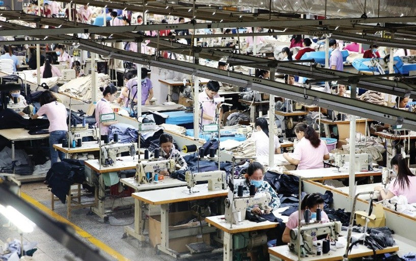 A factory showing the workers stitching fabric together at their respective stations.