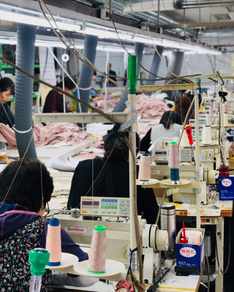 A factory showing the workers stitching fabric together at their respective stations.